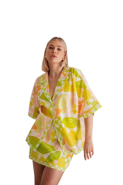 Woman wearing a colorful patterned pajama set with citrus fruit design.